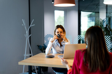 Two women collaborating in a modern office space during daytime
