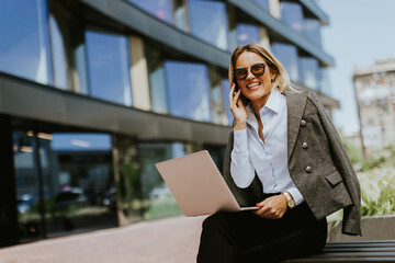 Businesswoman engaged in a call outside a modern office building, midday
