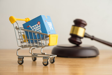 Trolley, online shopping boxes and hammer judge on wooden background. Consumer rights and...