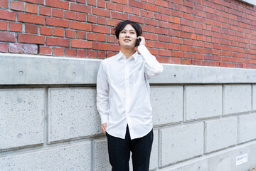 壁にもたれて電話をしている男性