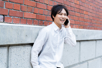 壁にもたれて電話をしている男性