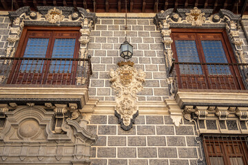 Facade of a house in Granada with a stone shield and wooden windows. Spain.