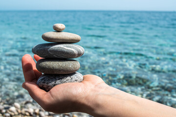 Stones stacked in a pyramid on a hand sunny day, pebble beach, Mediterranean sea