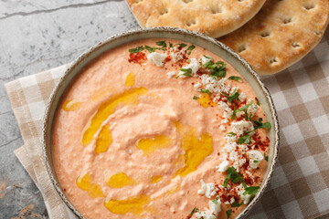 Tirokafteri feta cheese paste made from roasted bell peppers, Greek yogurt, olives oil and garlic closeup on the bowl on the table. Horizontal top view from above