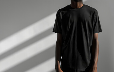 Man Standing in Black T-Shirt with Sunlight and Shadows on Neutral Background, Mockup
