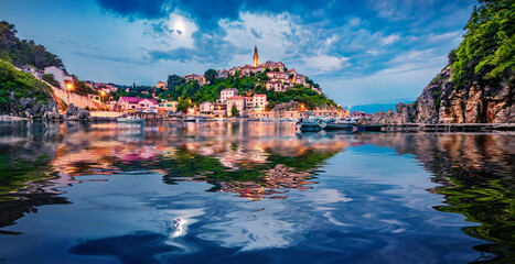 Illuminated old building of Vrbnik  port reflected in the calm waters of Adriatic sea. Picturesque...