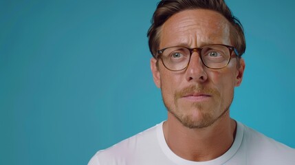 Fototapeta premium A tight shot of someone donning glasses and a white T-shirt against a backdrop of a blue wall