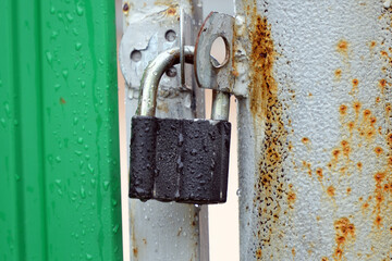 Small closed padlock hanging on the hinges