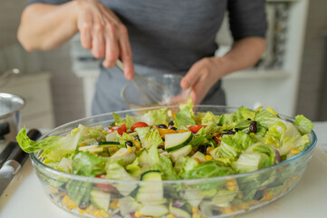 Woman preparing salad with fresh dressing 