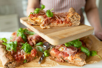 Hand holding or serving a fresh piece of healthy whole wheat pizza