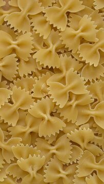 Italian farfalle pasta background. Table spin. Vertical video.