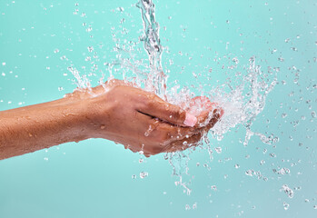 Fototapeta premium Studio, splash and water in hands of woman for clean with wellness, bacteria prevention and skincare hydration. Dermatology, liquid drops and model cupping palm for shower hygiene by blue background
