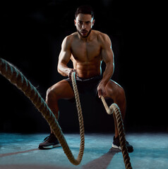 Man, portrait and fitness with battle rope for workout, training or intense exercise on a black...