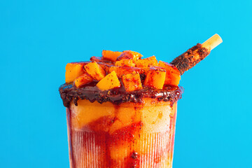 Mangonada, typical mexican mango smoothie on blue background. Close up.