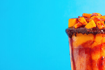 Mangonada, typical mexican mango smoothie on blue background. Close up.