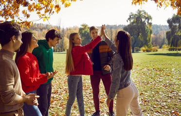 Happy smiling friends enjoy autumn walk in the park and have fun outdoors. Young beautiful girls...