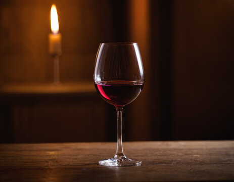 Un calice di vino rosso in una cantina, tra botti di legno e scaffali pieni.
