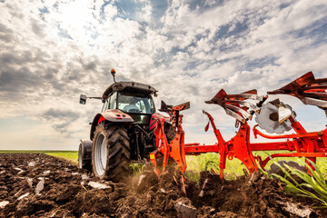 Powerful tractor turns the soil, readying the field for planting under a dramatic sky