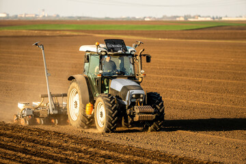 Farmer operating a tractor for sowing crops on fertile farmland, showcasing modern agriculture
