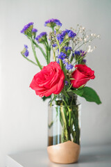 A bouquet of fresh roses with baby breath in a glass water jar on white background.