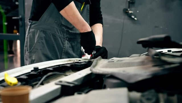 close up At a service station master auto mechanic unscrews bolts on the interior panel of a white car