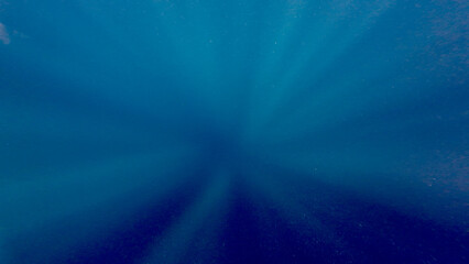 Rays of light on a blue background. The sun's rays sinking into the abyss of the ocean. The rays of the sun converge towards the center in the water column.