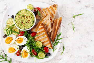 Healthy breakfast. Boiled egg, guacamole, toast and fresh salad. Top view, above