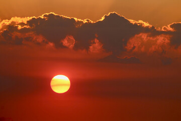 Obraz premium Red sunset. The sun's disk turns the sky red during sunset. The setting sun behind the clouds.