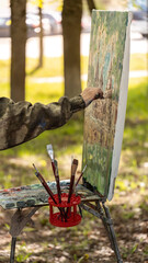 An artist is immersed in capturing the essence of nature, painting en plein air with an array of...
