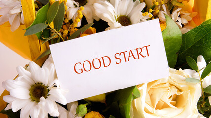 Text GOOD START written on a business card placed in a gift bouquet of flowers.