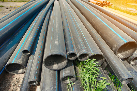 Polyethylene pipes stacked on the ground. Black pipe for new water supply network. Construction site with HDPE polyethylene pipes ready for installation, improvement of the water supply system.