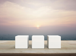 Three white block cubes on wooden table over modern city tower and skyscraper at sunset, vintage...