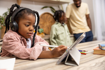 Little female pupil using her tablet for remote learning attending online classes
