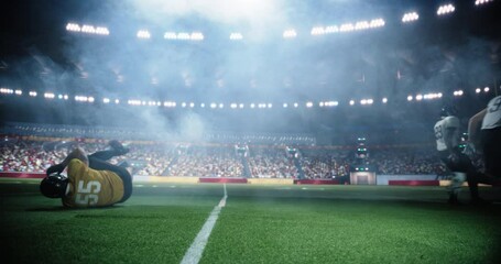 American Football Players Compete in a Stadium, Illuminated by Bright Lights With a Cheering Crowd in the Background. Athletes Play an Intensive Dynamic Game, Tacle, Try to Score a Touchdown