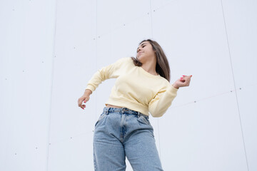 plus size woman wearing casual clothes dancing on white wall background in the street
