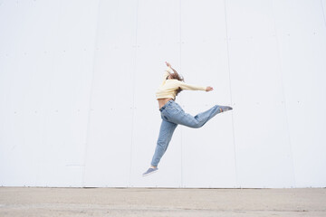 plus size woman wearing casual clothes dancing on white wall background in the street