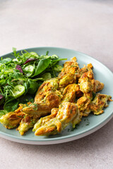 Fried zucchini flowers in batter and mix salad with cucumbers close up
