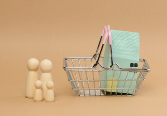 A wooden house in a miniature cart and wooden men of a family with children.