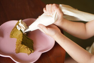 シフォンケーキに絞り袋で生クリームを絞ろうとしている女の子