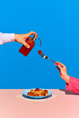 Playful image with plate of spaghetti with meatballs and hand holding soap dispenser with ketchup...