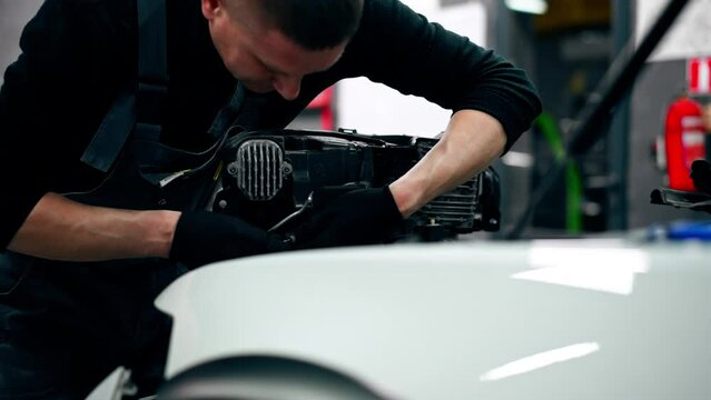 close-up At a service station master auto mechanic disconnects the wires from the headlight