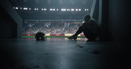 Tired American Football Player Sitting Alone in Stadium Tunnel, Helmet on Ground. Emotional Male Athlete Reflecting on a Failed Game, Coping with a Defeat, Showing Resilience After Championship Game