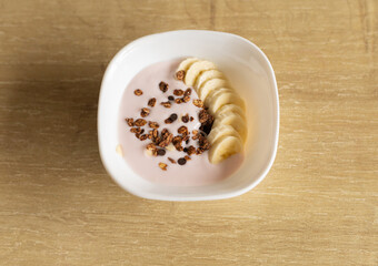 granola with yogurt and banana slices in a white plate