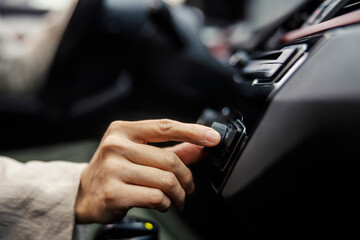 Close up of female's hand turning on radio in a car.
