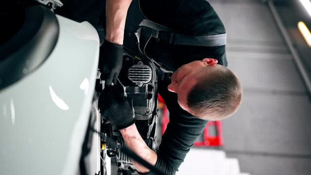 vertical video close-up At a service station master auto mechanic disconnects the wires from the headlight