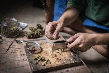 A man prepares marijuana on a cutting board to smoke, person who smokes drugs, drug addict, Drugs addiction and withdrawal symptoms concept. drugsInternational Day against Drug Abuse.