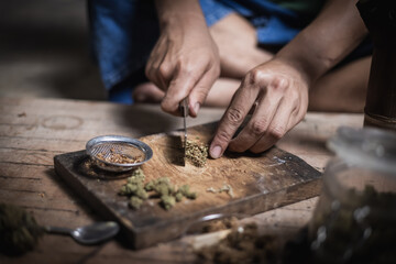 A man prepares marijuana on a cutting board to smoke, person who smokes drugs, drug addict, Drugs addiction and withdrawal symptoms concept. drugsInternational Day against Drug Abuse.