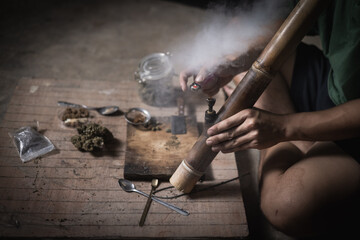 A man prepares marijuana on a cutting board to smoke, person who smokes drugs, drug addict, Drugs addiction and withdrawal symptoms concept. drugsInternational Day against Drug Abuse.