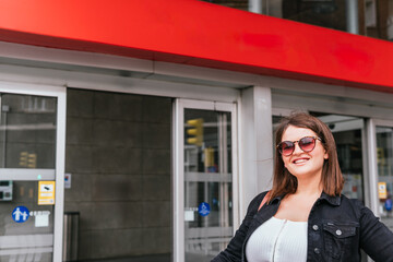 A happy, smiling woman waits at the doors of a train station