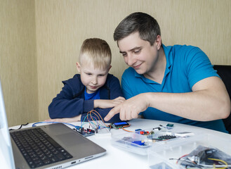 Programming for children. A teacher teaches a child at a robotics and IT school. Boy learning to...